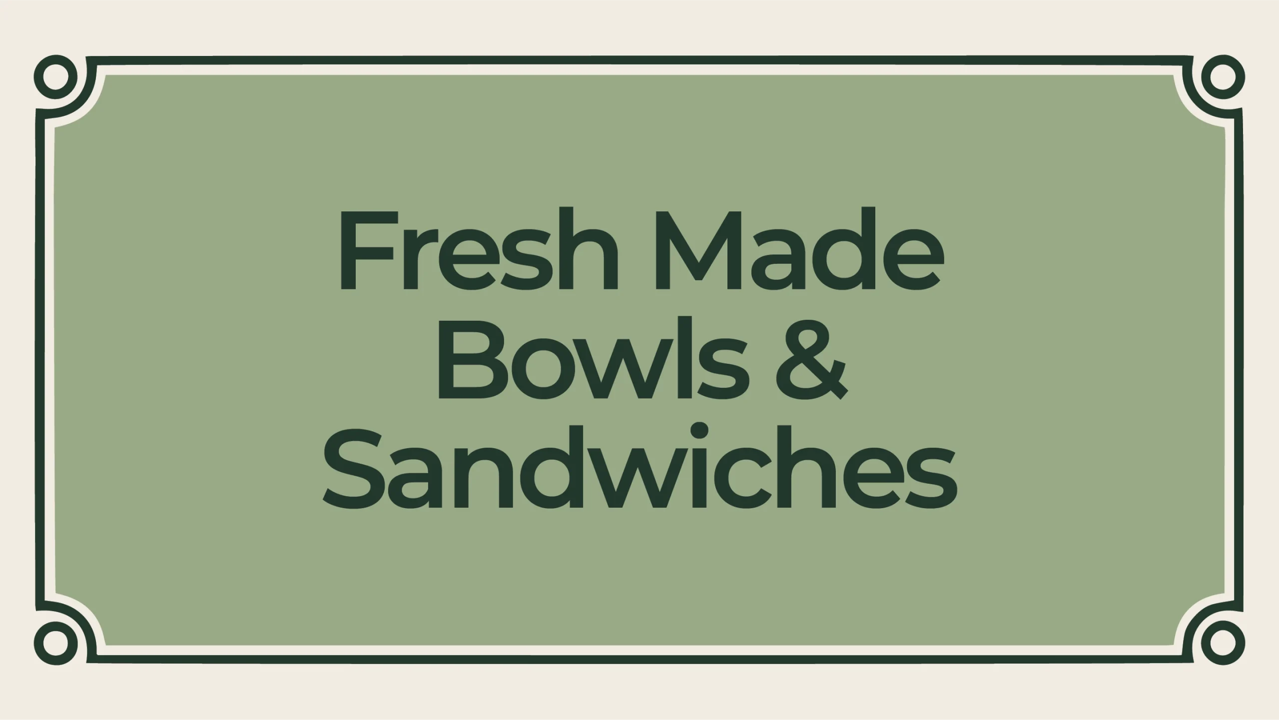 Signboard reading 'Fresh Made Bowls & Sandwiches' on a green panel with ornate border.